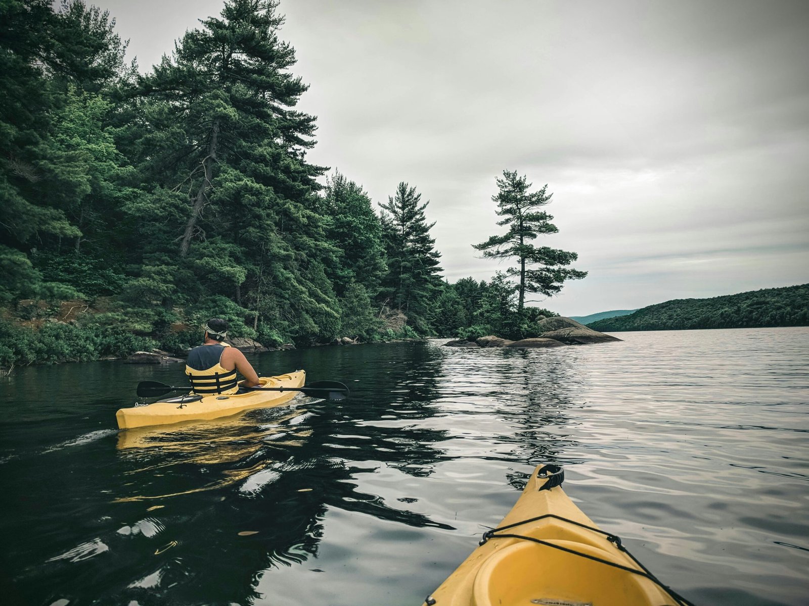 person riding yellow kayak on lake during daytime